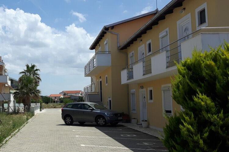 um carro estacionado num parque de estacionamento ao lado de um edifício em Apartments Lug 2 new and comfortable with pool em Privlaka