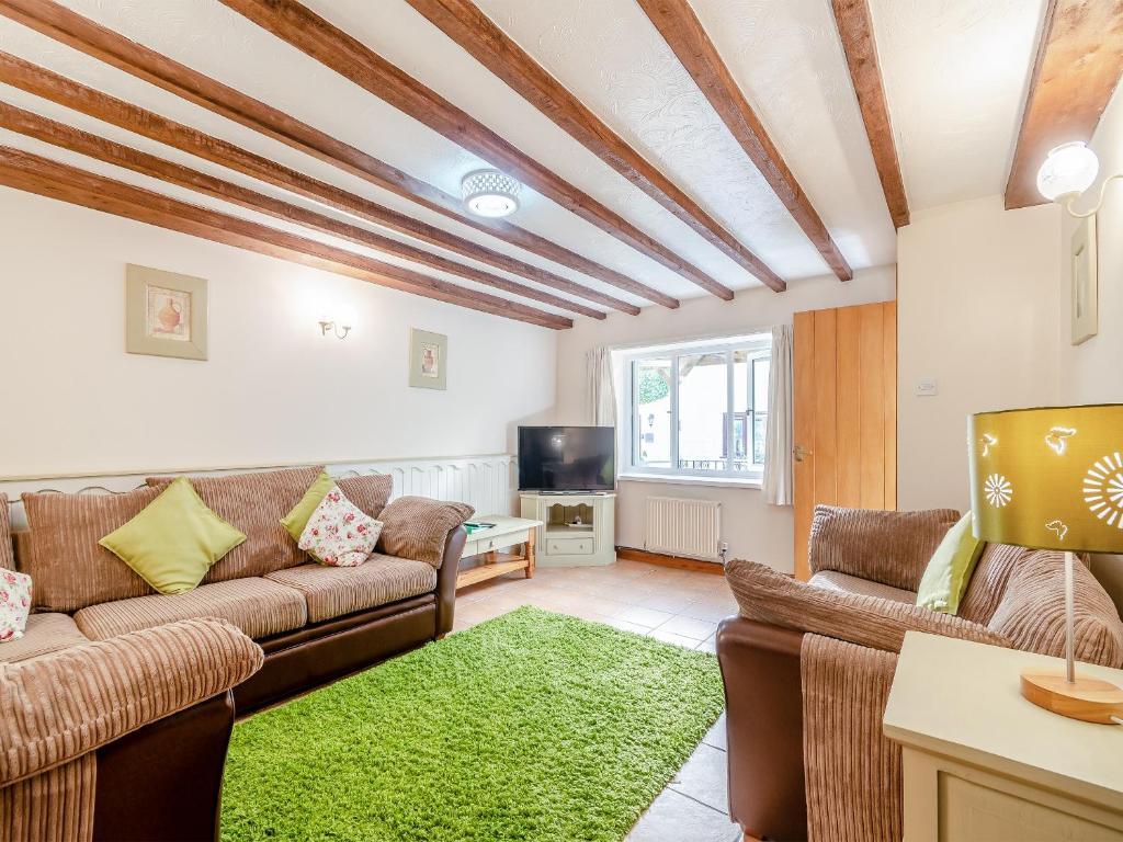 a living room with couches and a green rug at Primrose Cottage- Uk45597 in Verwick
