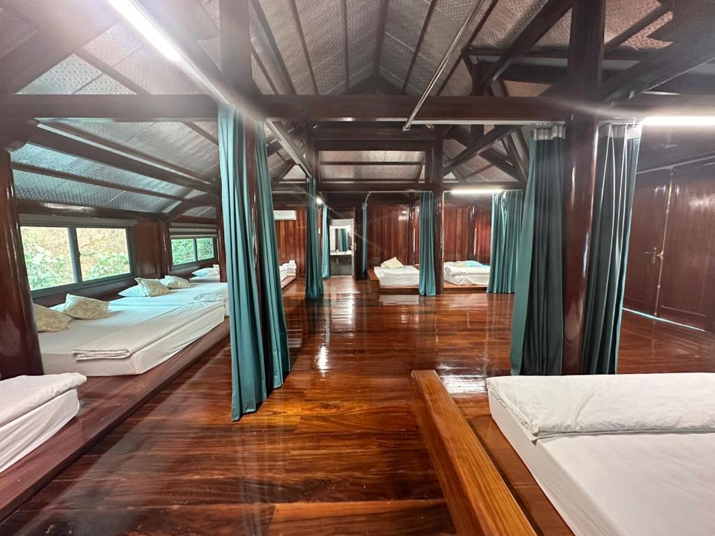 um quarto com 3 camas e um piso de madeira em khách sạn thúy phương 2 em Hào Gia