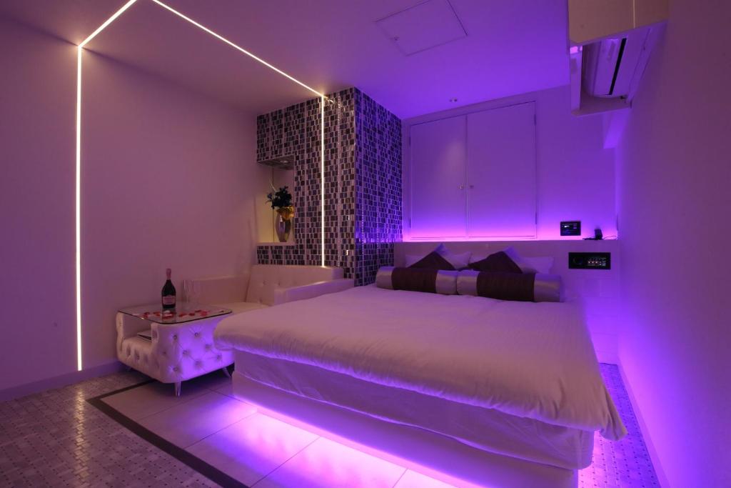 a bedroom with a white bed with purple lighting at Hotel Blanche 大人専用 in Tokyo