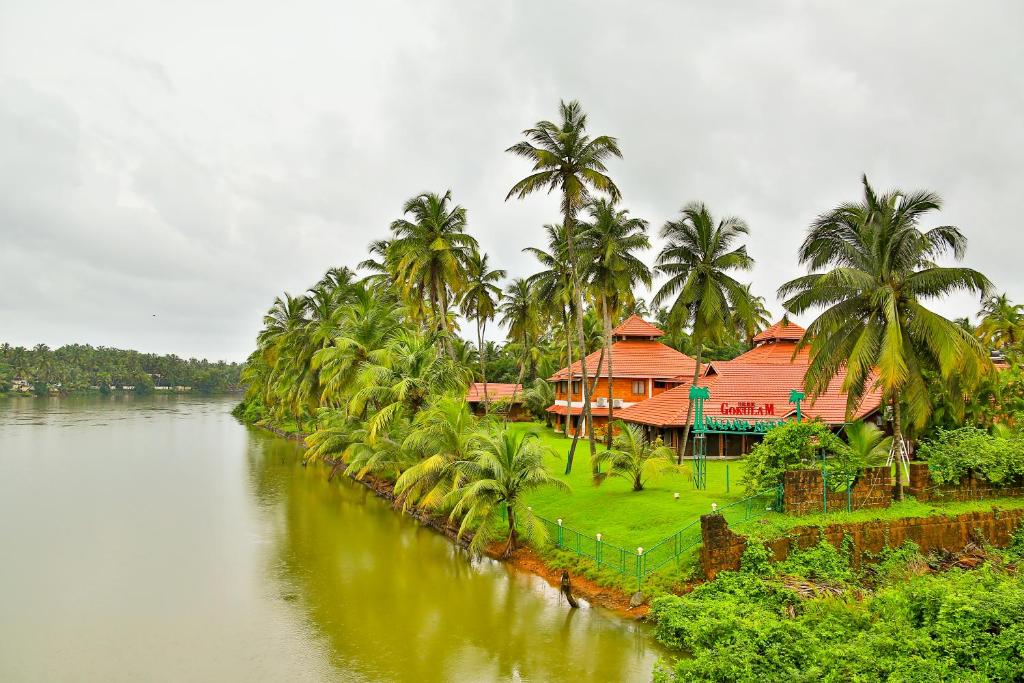 una casa junto a un río con palmeras en SREE GOKULAM NALANDA RESORTS, en Nīleshwar