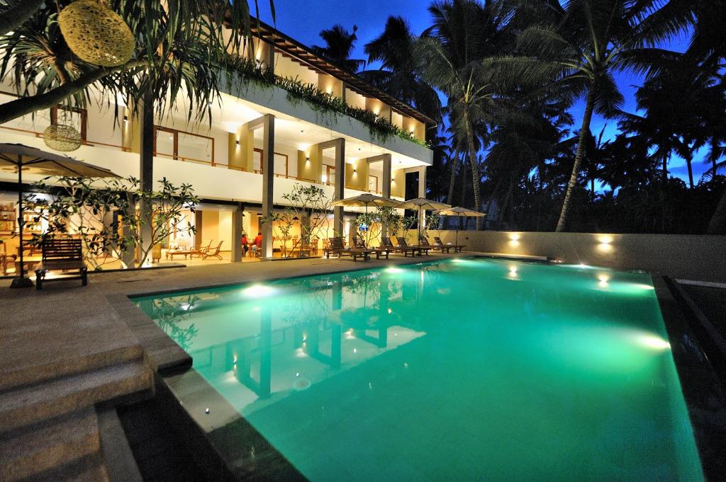 a swimming pool in front of a house at night at Tantalize Beach in Hikkaduwa