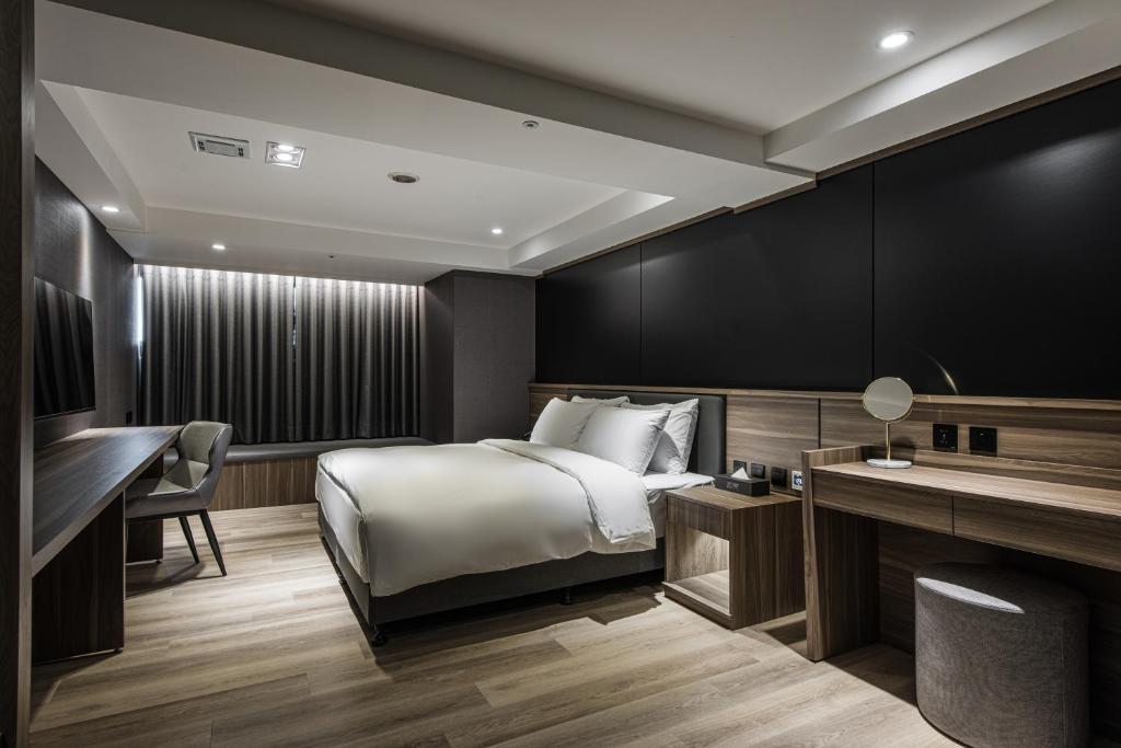een hotelkamer met een bed en een bureau bij Autumn Willow Hotel in Taichung