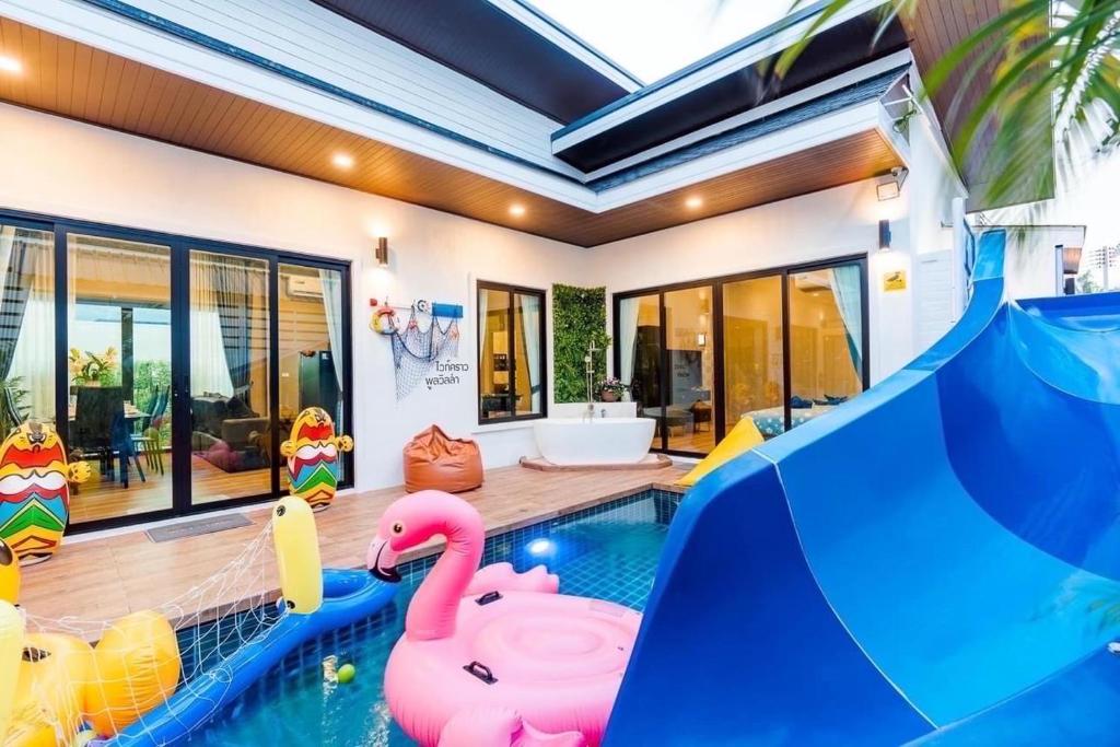 een zwembad met een glijbaan en opblaasbare flamingo's in een huis bij White Cloud Luxury Pool Villa Cha Am in Cha Am