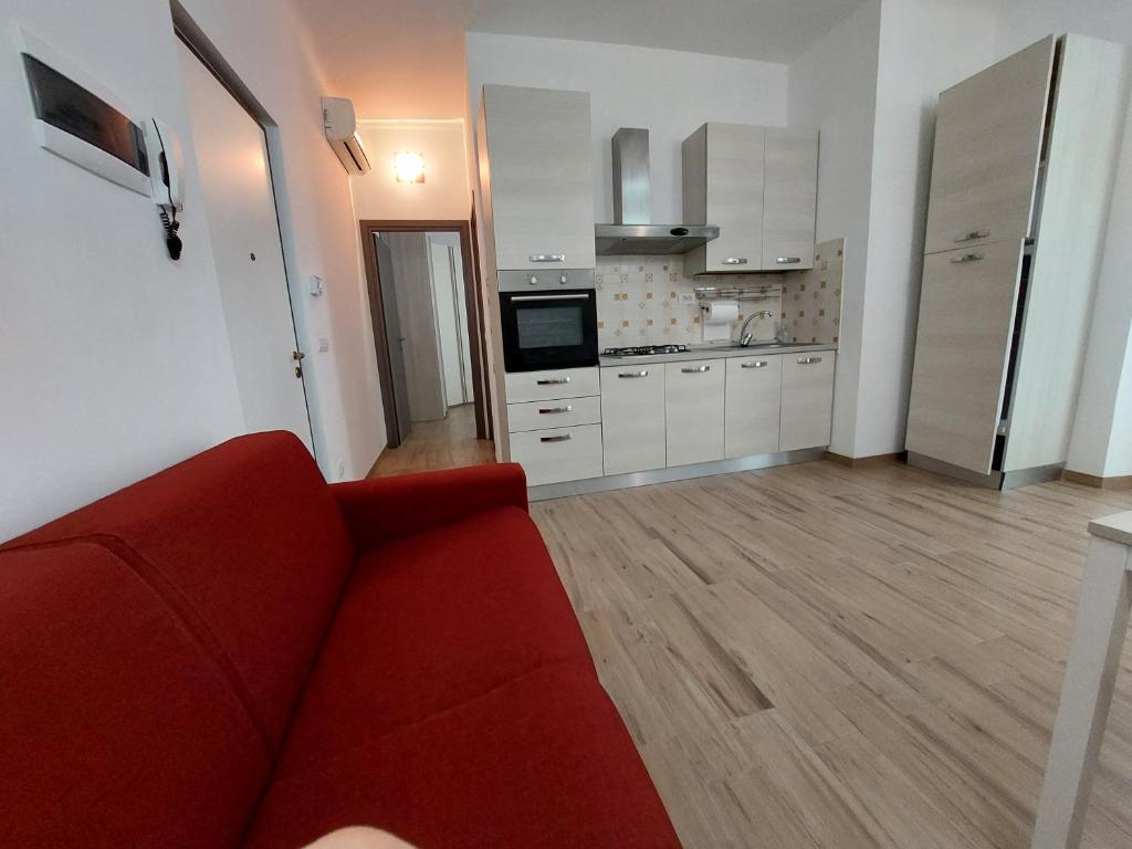 a living room with a red couch and a kitchen at Bilocale la Magnolia in Savona