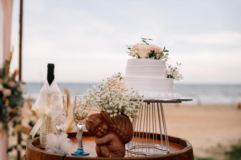 a wedding cake and wine glasses on a table at the beach at Cam Binh Resort Lagi in La Gi