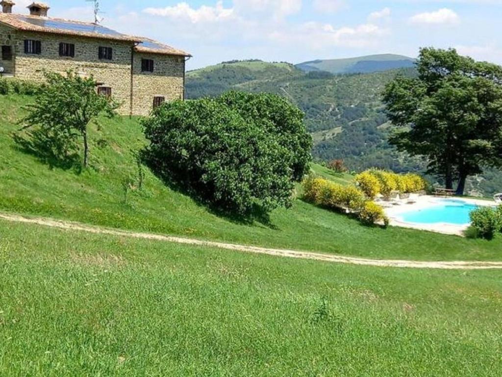 una casa en una colina con césped y piscina en Stunning Villa in Apecchio with Jacuzzi, en Apecchio
