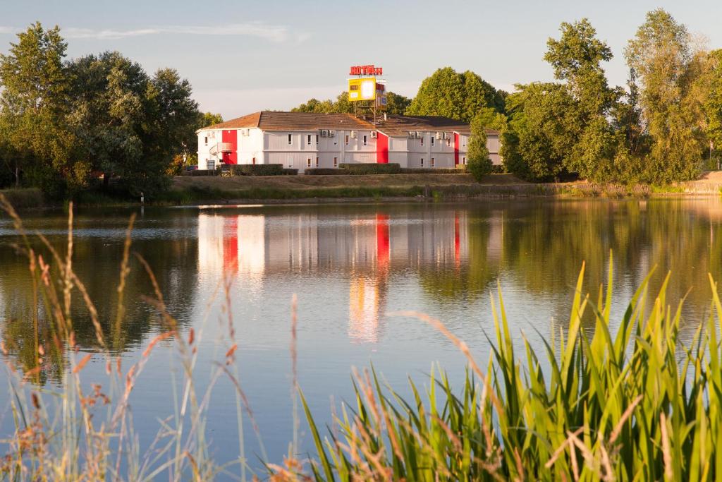 a house on the shore of a lake with a lighthouse at The Originals Access, Hôtel Bordeaux Lac in Bruges