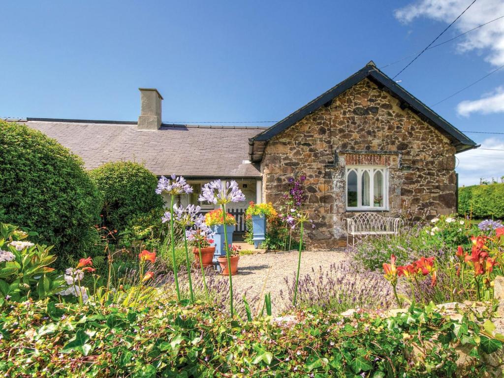a stone house with a garden in front of it at Swallow Cottage in Llandwrog