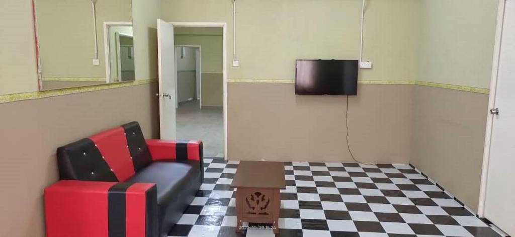 Cette chambre dispose d'une chaise, d'une télévision et d'un sol en damier. dans l'établissement Hotel Lii View Labis, à Labis