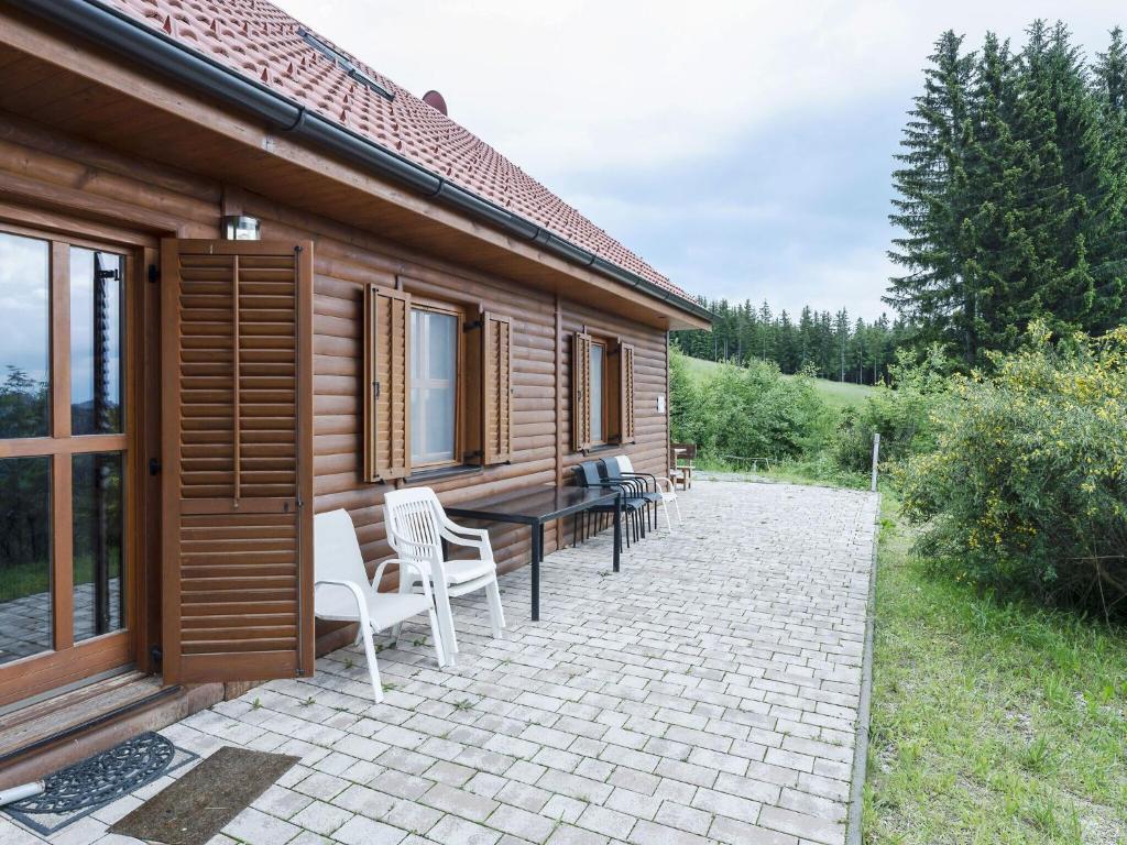 un patio con mesa y sillas junto a una casa en Detached wooden chalet in Liebenfels Carinthia near the Simonh he ski area, en Liebenfels
