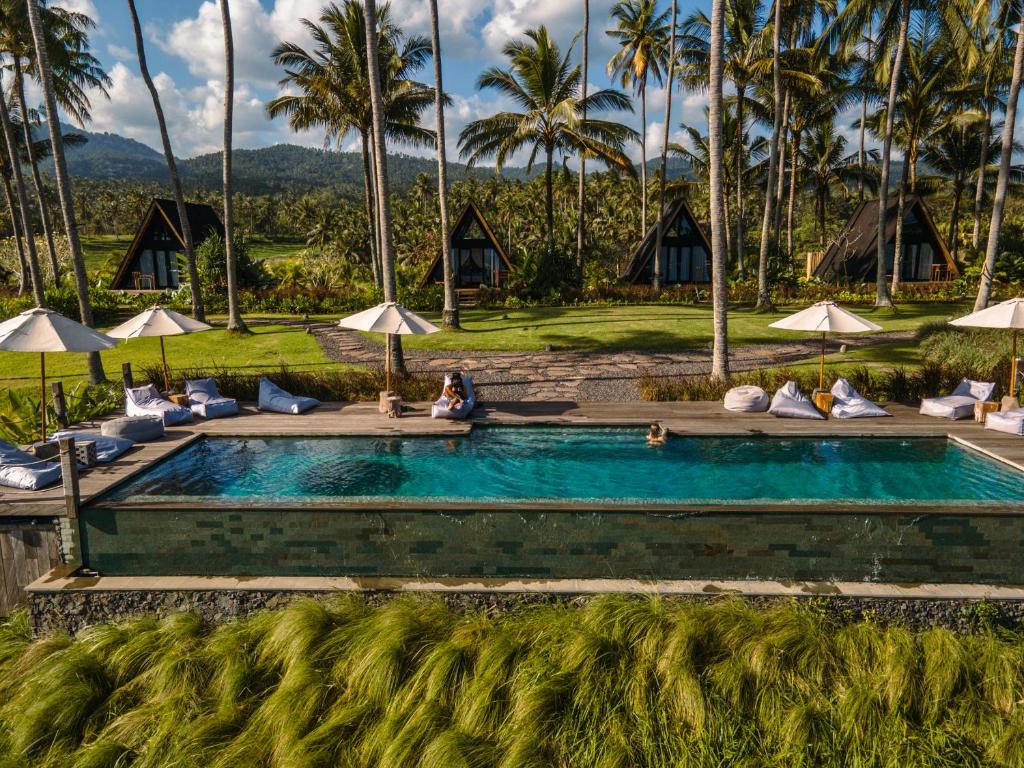 a pool at a resort with palm trees at Desa Cabins in Balian