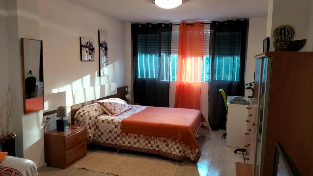 a bedroom with a bed and a dresser and windows at Miniloft en la playa in Alicante