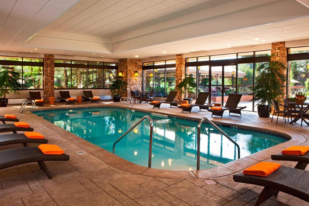 uma piscina no átrio do hotel com cadeiras e mesas em Denver Marriott West em Golden