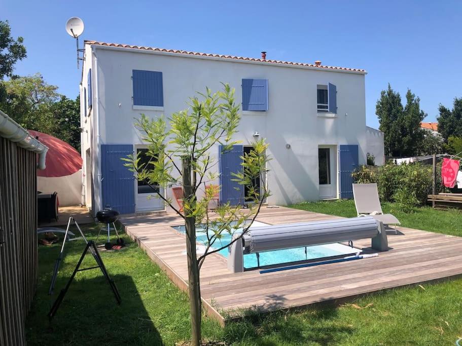 ein Haus mit einer Holzterrasse und einem Pool in der Unterkunft Maison Oléron avec piscine in Le Trait dʼUnion