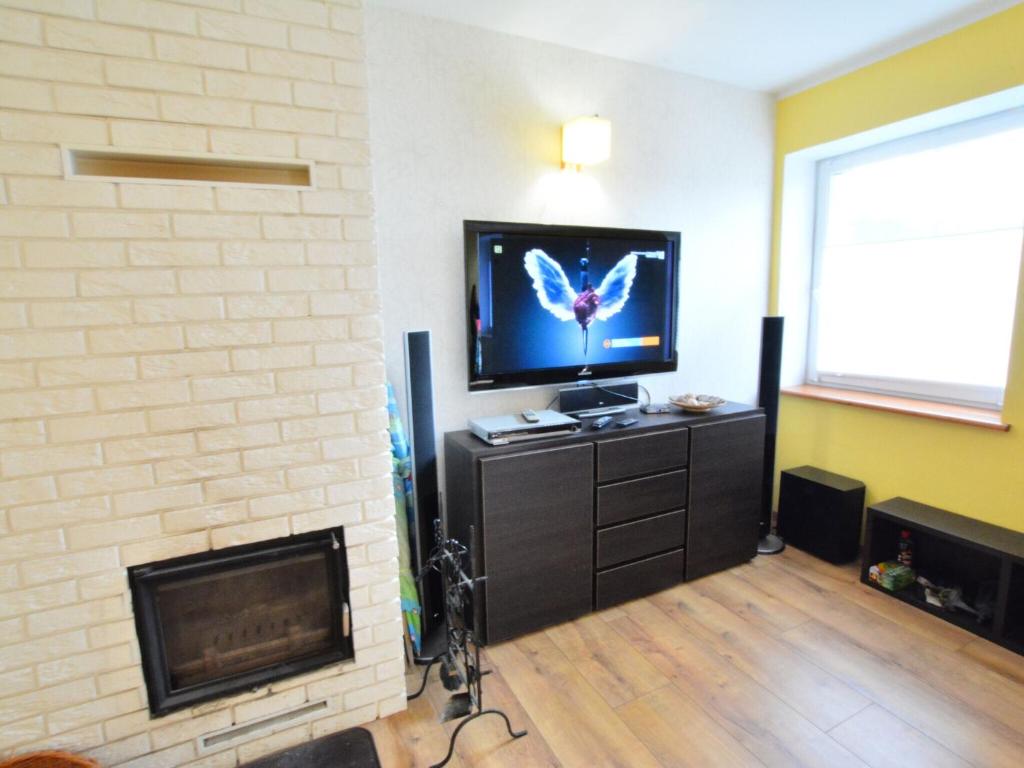 a living room with a tv and a fireplace at Cozy cottage for 2 people near the sandy beach in Pleśna