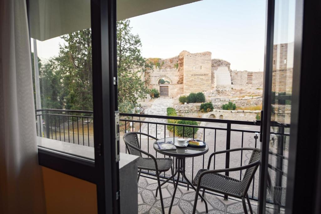 a balcony with a table and chairs and a view of the ruins at Kallinos Boutique Hotel in Selcuk