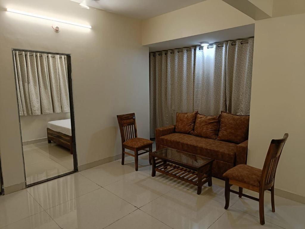 Hotel Charaksanjivani في نافي مومباي: غرفة معيشة مع أريكة ومرآة