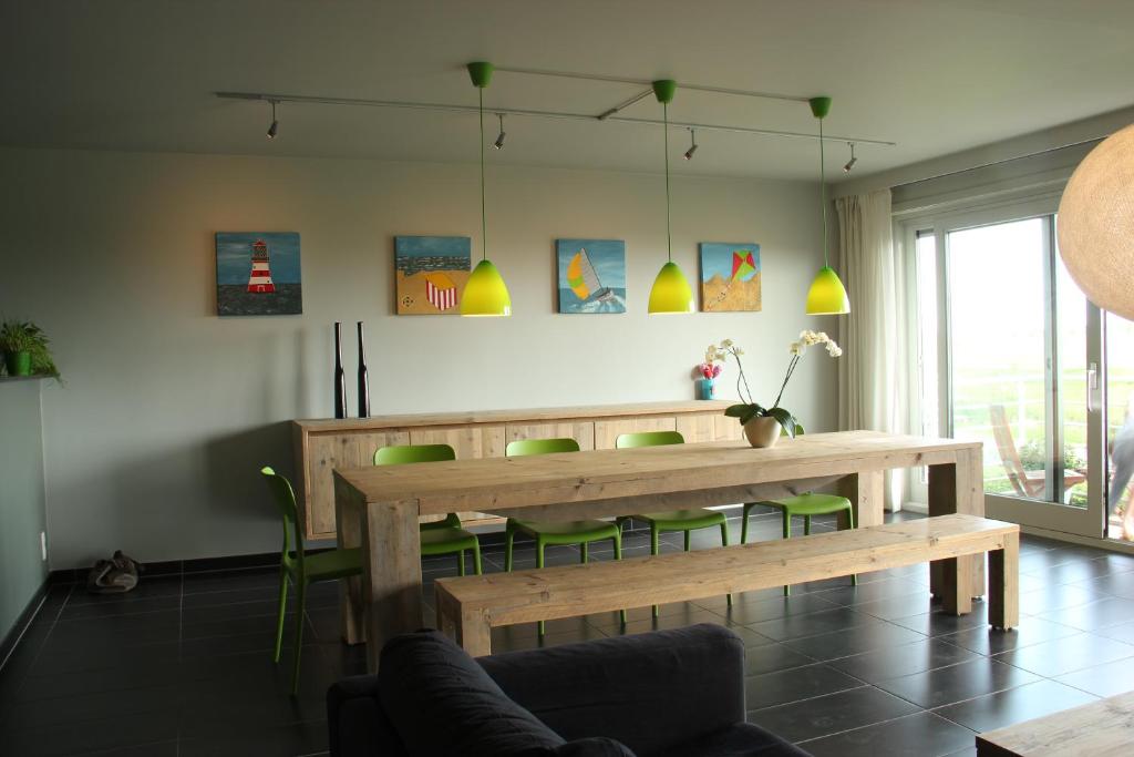 ニーウポールトにある"Zonnesteiger" ruim appartement met parkingのダイニングルーム(木製テーブル、緑の椅子付)