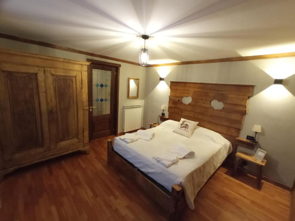1 dormitorio con 1 cama grande y cabecero de madera en La Randoulino, en Pomaretto