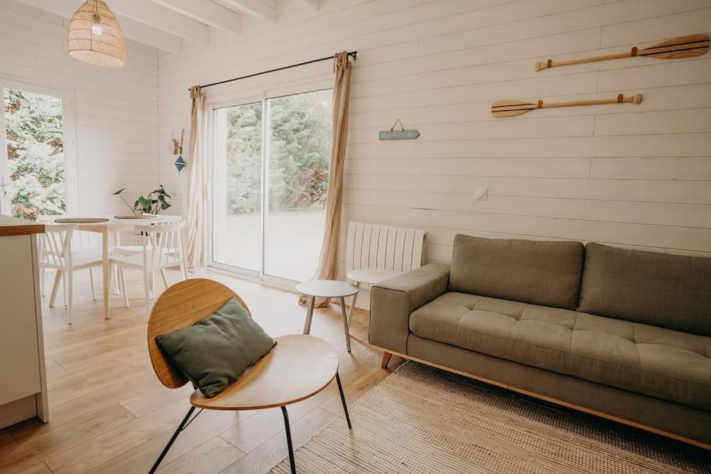 ein Wohnzimmer mit einem Sofa und einem Tisch in der Unterkunft Sous le Saule, entre lac et océan in Naujac-sur-Mer