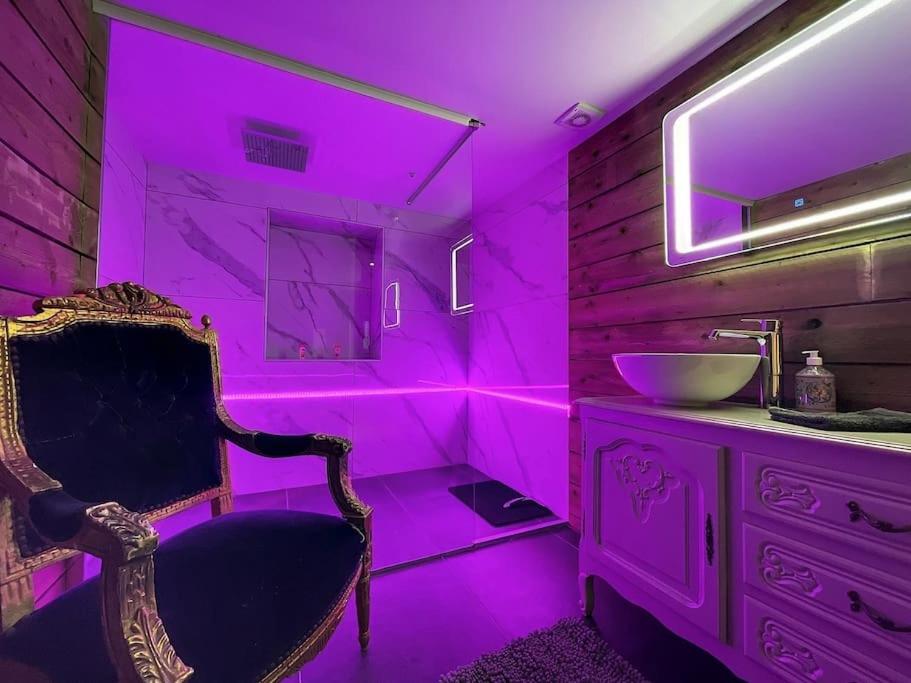 ein Bad mit rosafarbener Beleuchtung, einem Stuhl und einem Waschbecken in der Unterkunft L'ancre céleste in Aywaille