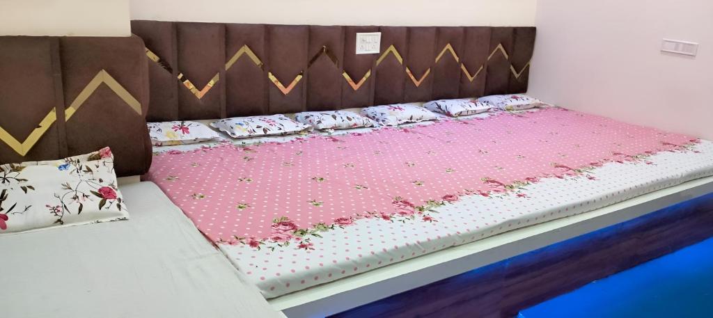 a bed with a wooden headboard with pink flowers on it at PRABHU PALACE in Ujjain