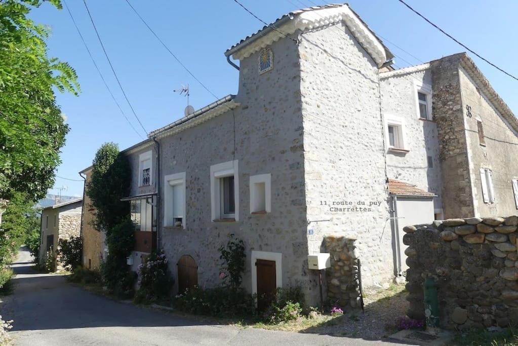 a large stone building with a stone wall at Maison de Village en pierres in Le Poët