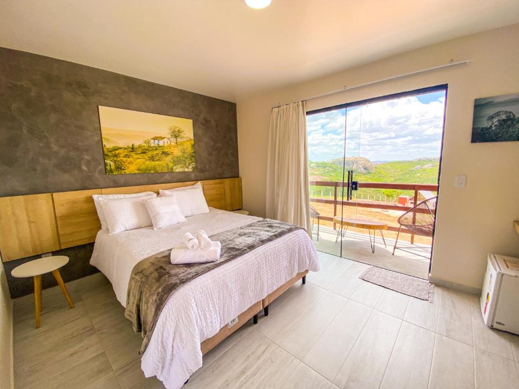 a bedroom with a large bed and a balcony at Entre Serras Gastropub e Chalés in Monte das Gameleiras