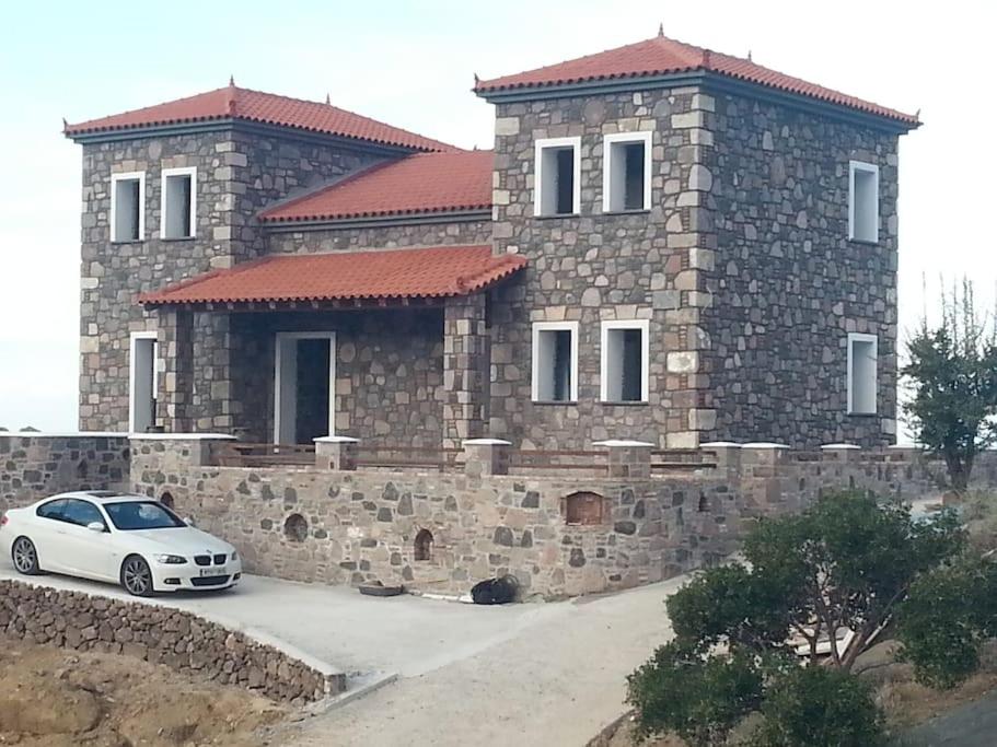 Molivos Castleview Luxury Villa في ميثيمنا: سيارة بيضاء متوقفة أمام منزل حجري