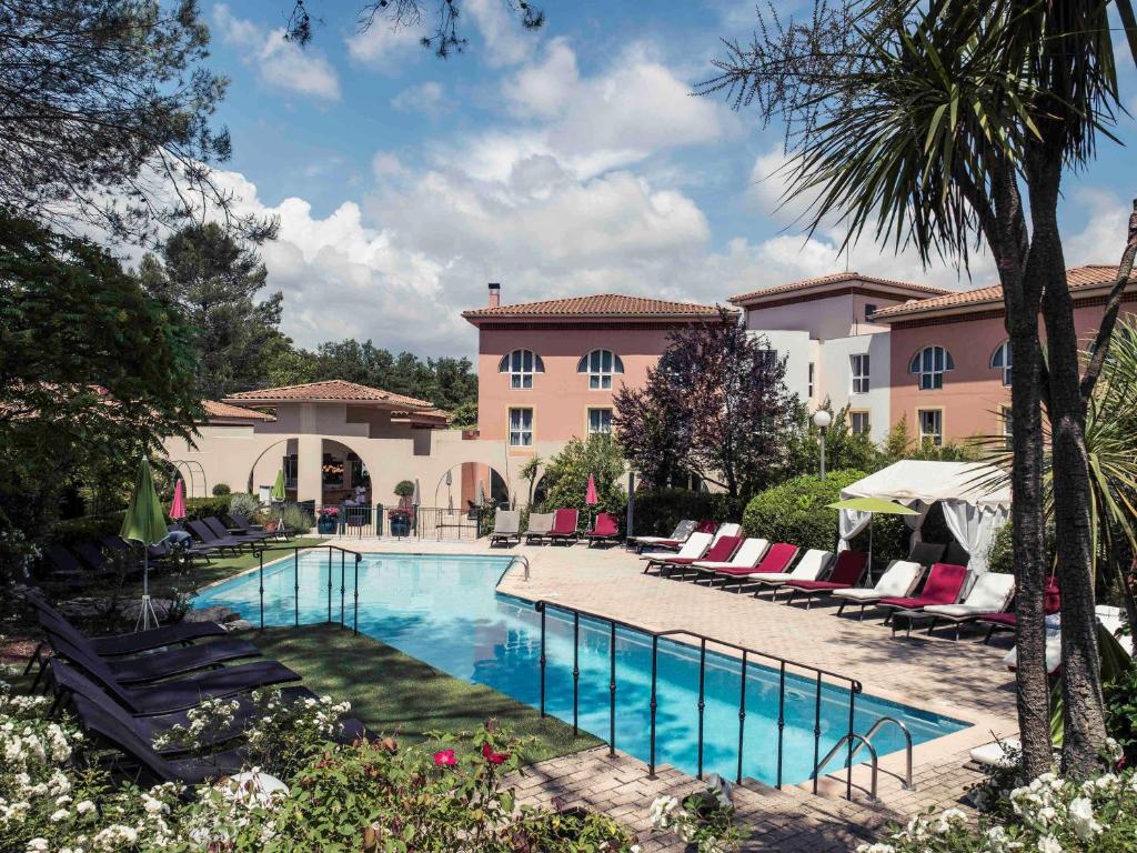 a swimming pool in front of a large building at Mercure Antibes Sophia Antipolis in Valbonne