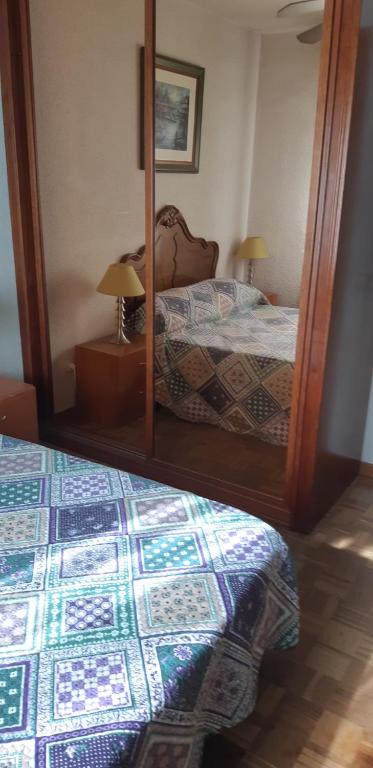 a bedroom with a mirror and a bed with a bed sqor at Habitación LCV in Madrid
