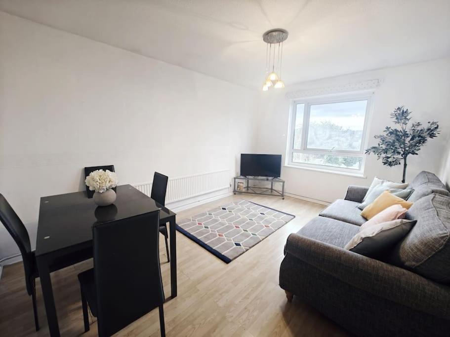 ein Wohnzimmer mit einem Sofa und einem Tisch in der Unterkunft City Airport Apartment in London