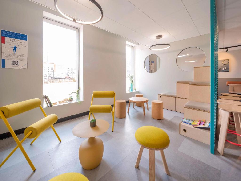 une salle d'attente avec des chaises et des tables jaunes dans l'établissement ibis budget Forbach Centre, à Forbach