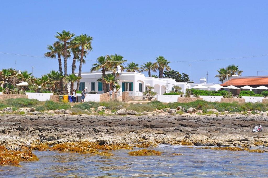 una casa sulla spiaggia con palme sullo sfondo di RESIDENCE OASI SUL MARE a Torre Suda