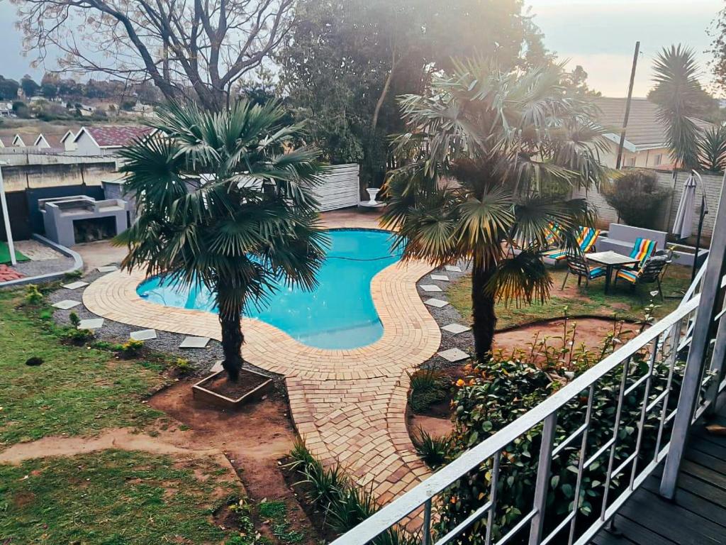 a swimming pool with two palm trees in a yard at Adante Lodge & Conferencing in Mthatha