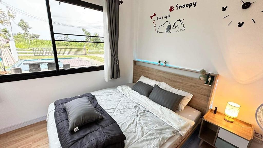ein Schlafzimmer mit einem Bett und einem Fenster mit einer Uhr an der Wand in der Unterkunft บ้านไออุ่น เขื่อนไม้เต็ง in Ban Na Thom