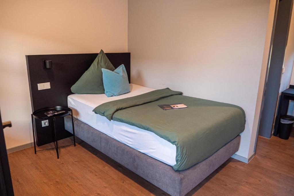 a small bedroom with a bed with blue and green pillows at Strandhaus Hagen in Hagen