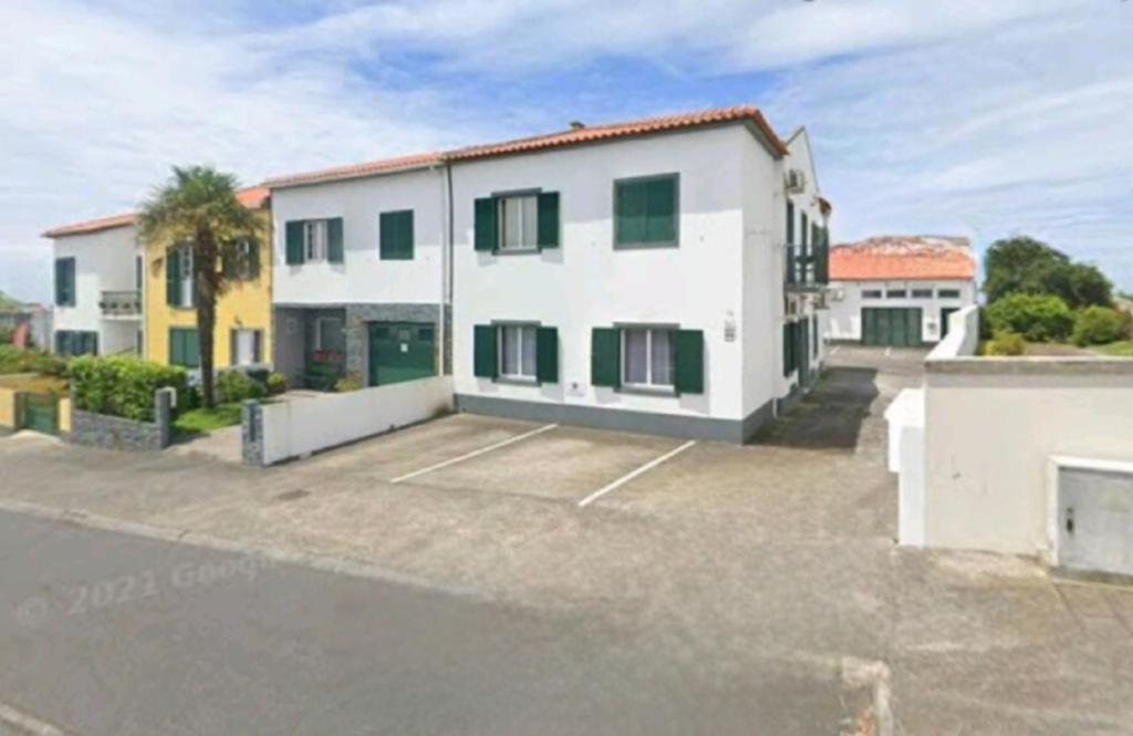 a large white house with a parking lot at Cozy apartment close to airport in Ponta Delgada