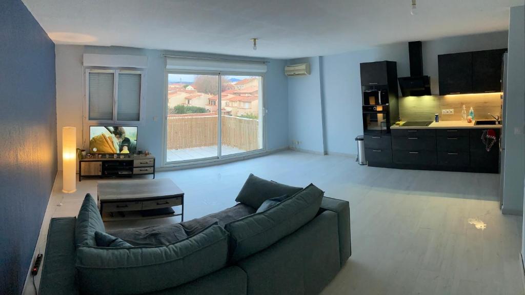uma sala de estar com um sofá e uma cozinha em Appartement 55m² avec vue sur Canigou et Parking em Rivesaltes