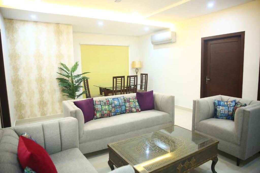 sala de estar con sofá, 2 sillas y mesa en Gulberg Suites, en Lahore