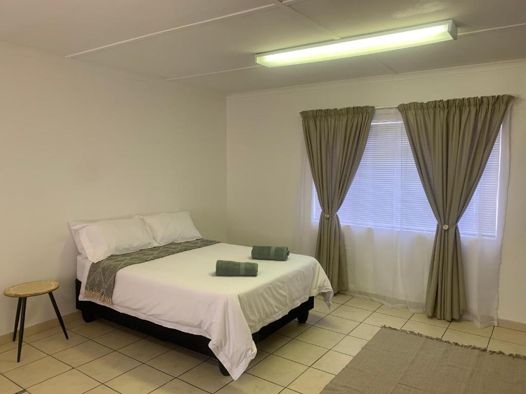 - une chambre avec un lit et une fenêtre avec des rideaux dans l'établissement Pioneerspark Self Catering, à Windhoek