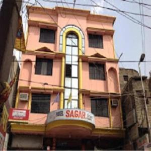 un bâtiment rose avec un panneau devant lui dans l'établissement Hotel Sagar Inn - Bihar, à Samastīpur