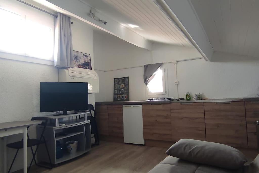 uma sala de estar com televisão e uma cozinha em Appartement T2, coin jardin. em Bernis