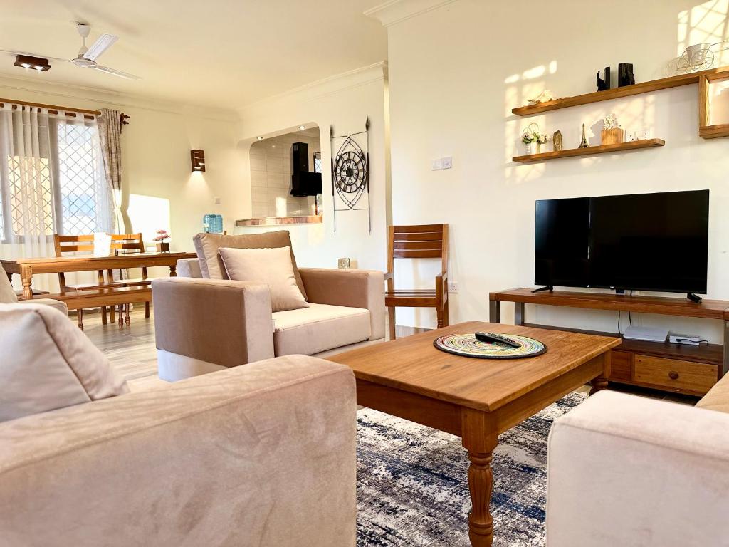 a living room with a couch and a tv at 3 Bedroom Luxury Villa-Sita in Diani in Kinondo