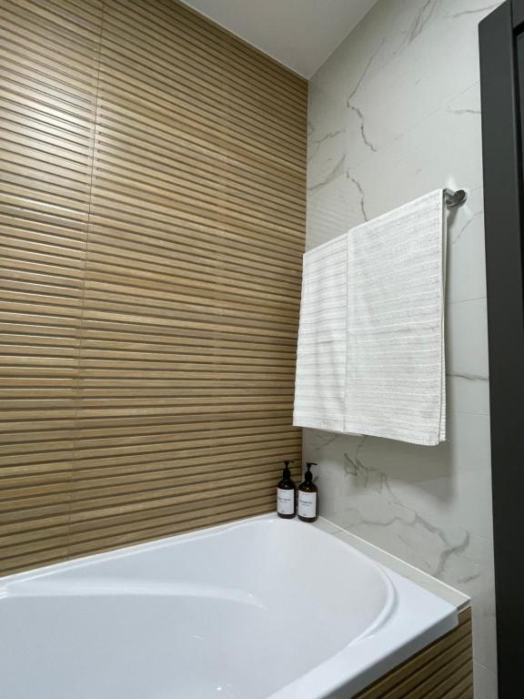 La salle de bains est pourvue d'une baignoire blanche et d'une serviette. dans l'établissement Apartament central 2 camere, à Râmnicu Vâlcea