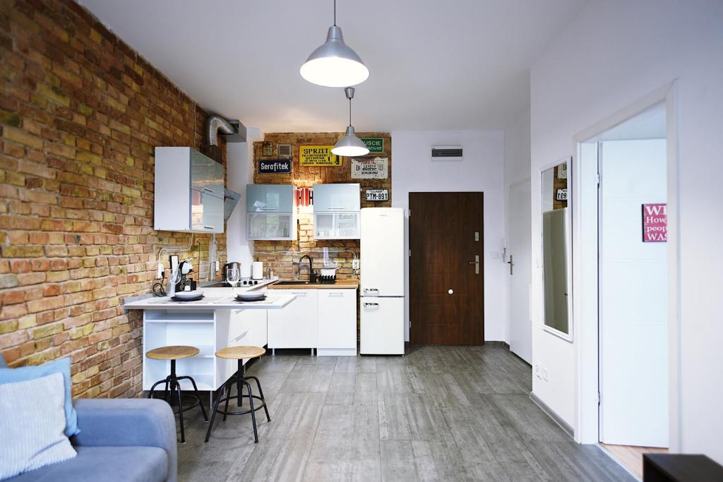 a kitchen with white cabinets and a brick wall at Mini Loft Janickiego in Szczecin