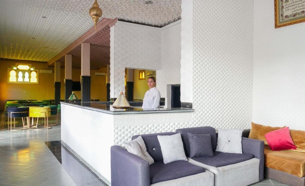 a man standing behind a bar with a couch at Hotel Warda in Ouarzazate