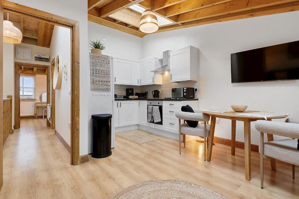 a kitchen and dining room with white cabinets and a table at The Hoxton Loft - Top Floor Shoreditch Apartment in London