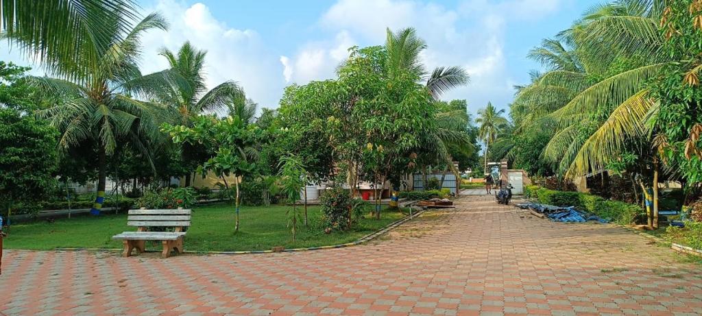 a park with a bench and some palm trees at KINGS COCO RESORT in Konārka